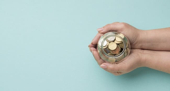 Manos con una hucha llena de monedas